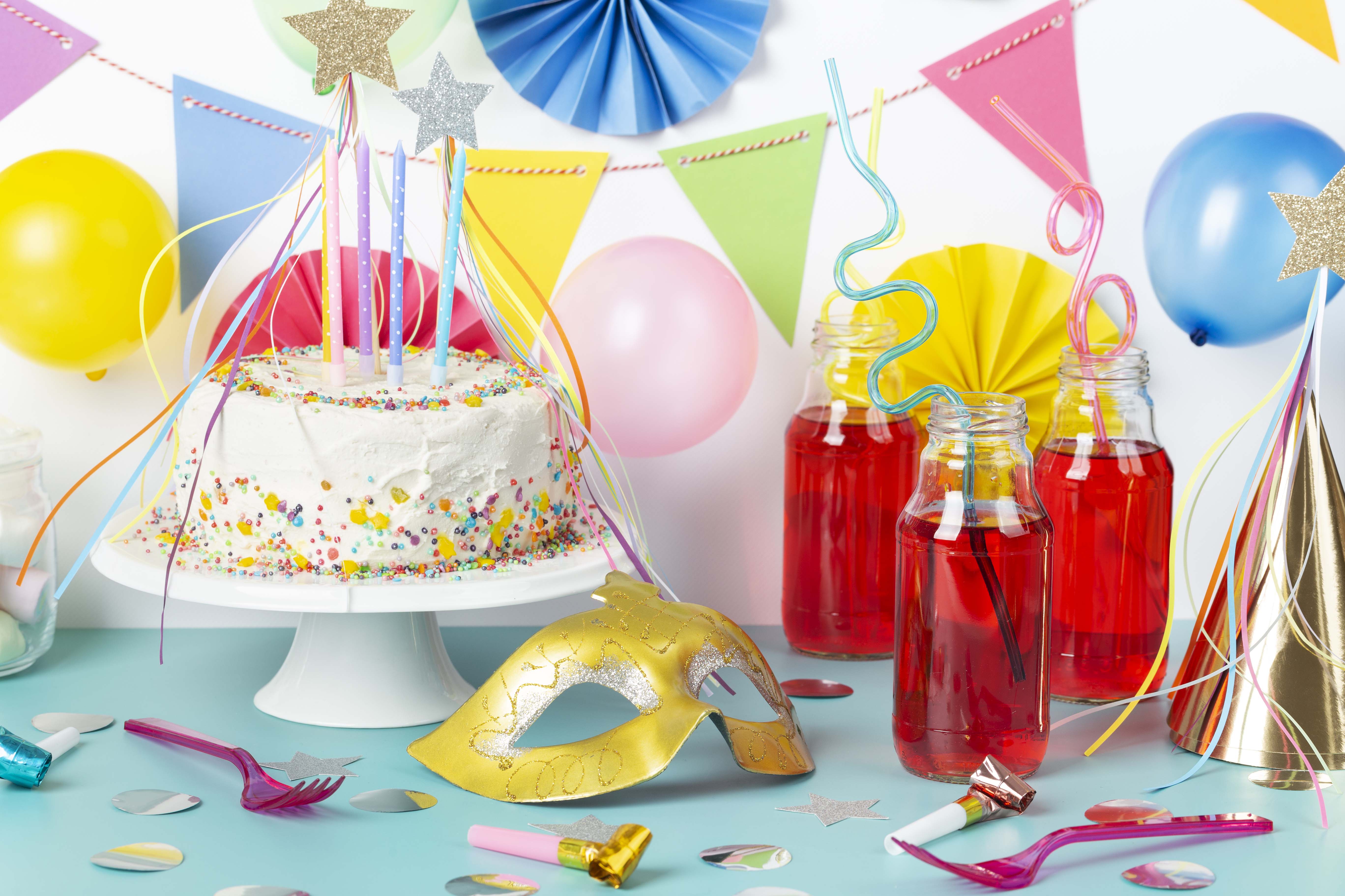 طاولة عيد ميلاد مزينة بألوان زاهية وفرحة مثل الوردي والأصفر والأزرق، مع كعكة ملونة، بالونات وتوزيعات تضفي أجواء مرحة واحتفالية